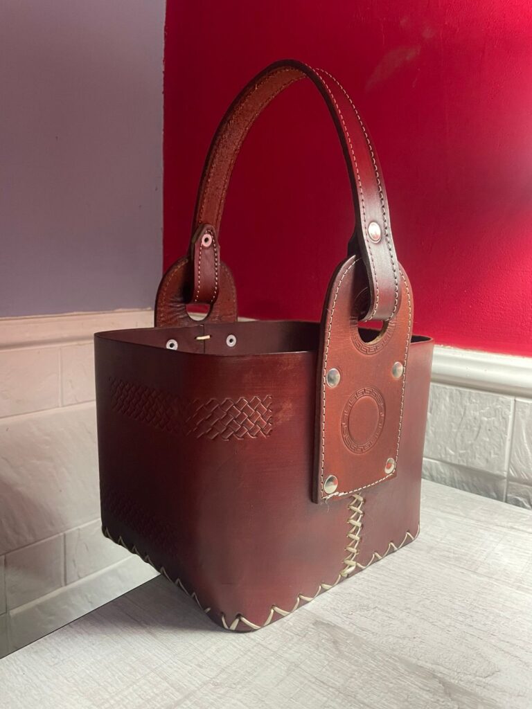 Matera de cuero artesanal con diseño cuadrado, ideal para transportar termo y mate. Costuras a la vista y grabados decorativos.