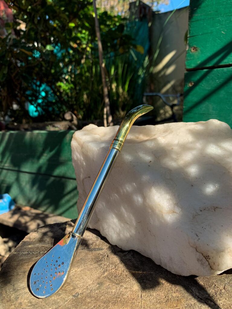 Bombilla de acero inoxidable con detalles dorados, diseño clásico y elegante, fotografía sobre piedra blanca.