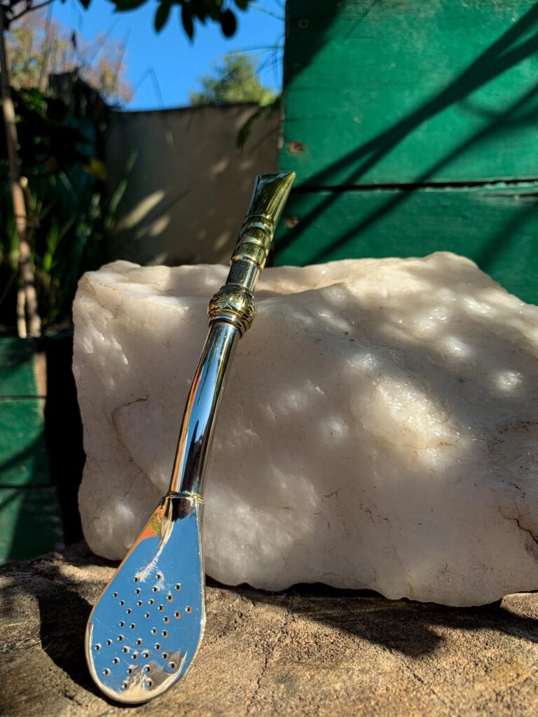 Bombilla de acero inoxidable con diseño estilo bambú, detalle dorado y terminación brillante, sobre fondo natural.